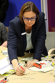 Teilnehmerin im World Café schreibt Gedanken auf