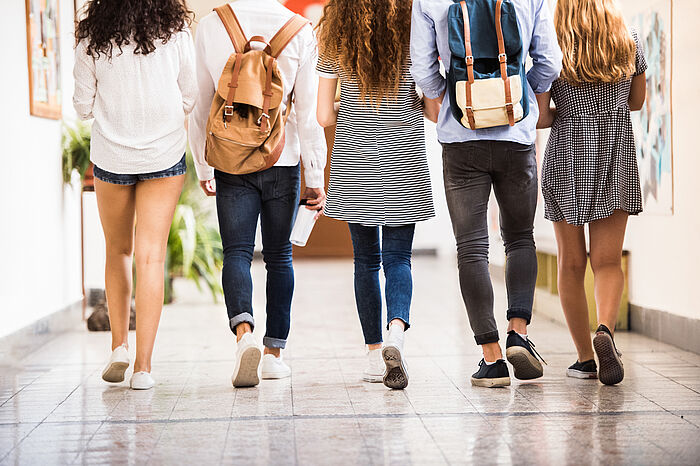 Fünf Schülerinnen und Schüler gehen einen Gang hinunter.