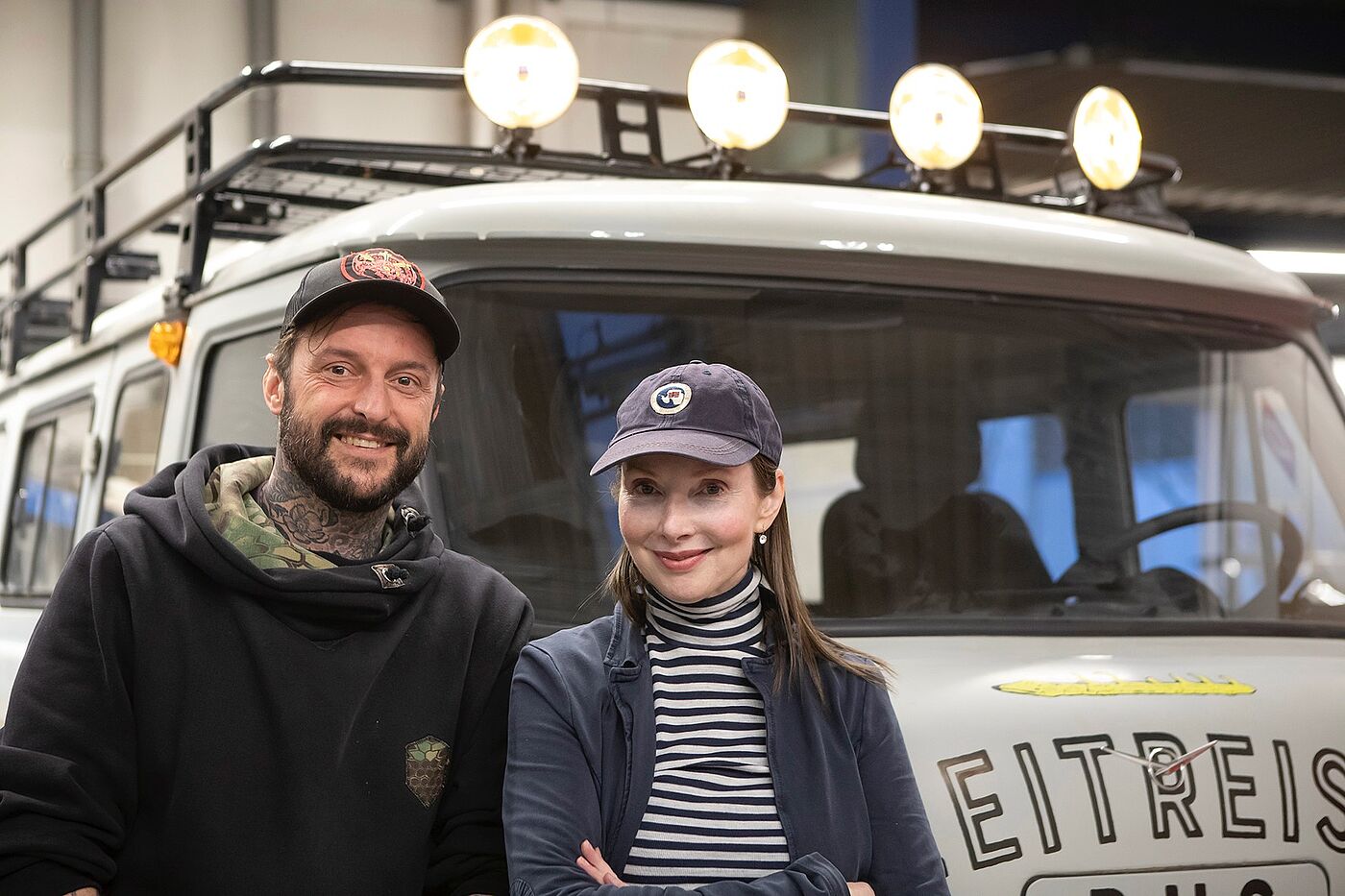 Ein Mann und eine Frau vor einem umgebauten Bus.