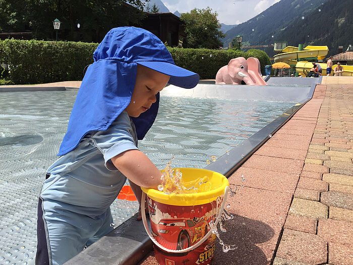 Baby im Freibad mit Sonnenschutz-Kleidung