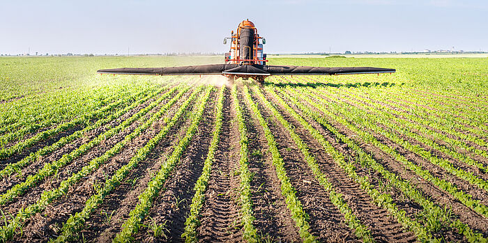 Ein Traktor der auf dem Feld Pestizide versprüht