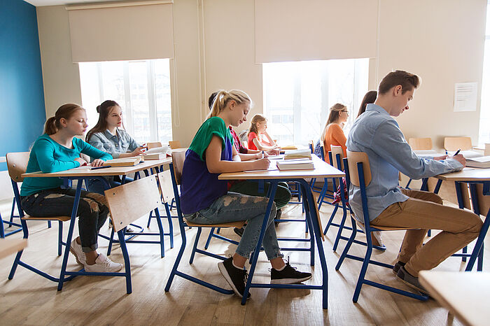 Junge Menschen die eine Prüfung schreiben und an ihren Tischen sitzen
