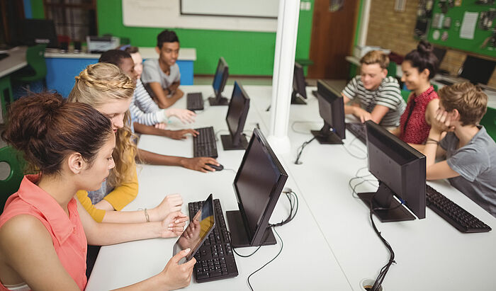 Schüler_innen arbeiten an Computern in Klassenzimmer.