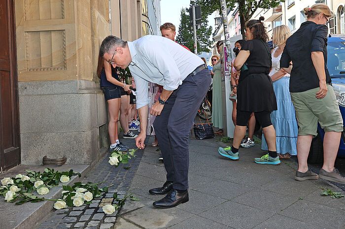 Dr. Tim Grüttemeier beim Niederlegen der Rose an den neuen Stolpersteinen.