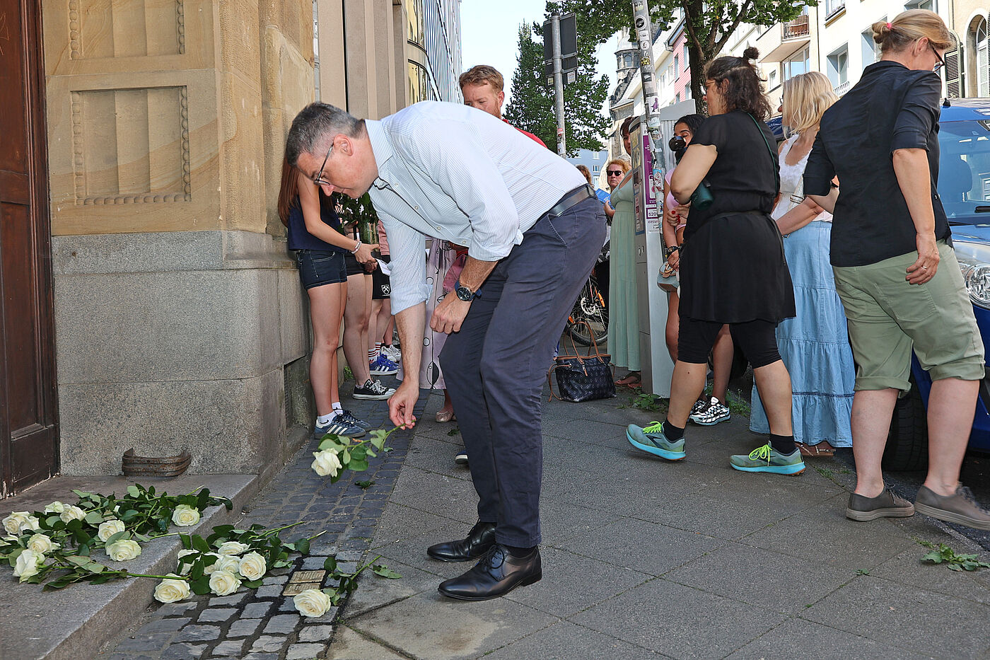 Dr. Tim Grüttemeier beim Niederlegen der Rose an den neuen Stolpersteinen.