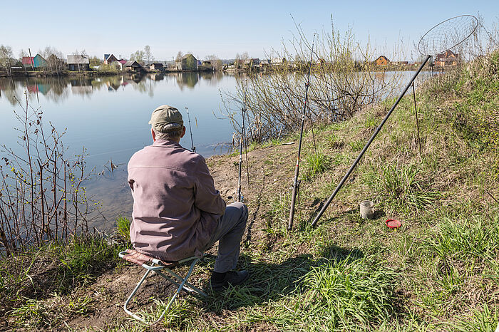 Ein Angler auf einem Klappstuhl der an einem See angelt