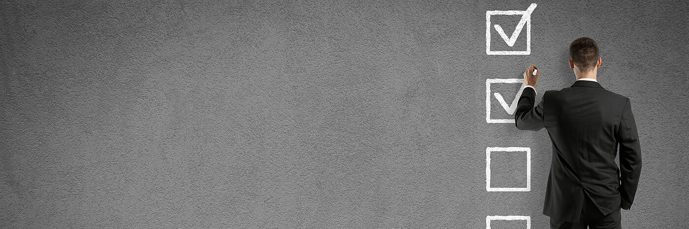 Mann, der riesige Checkliste an Tafel abhakt