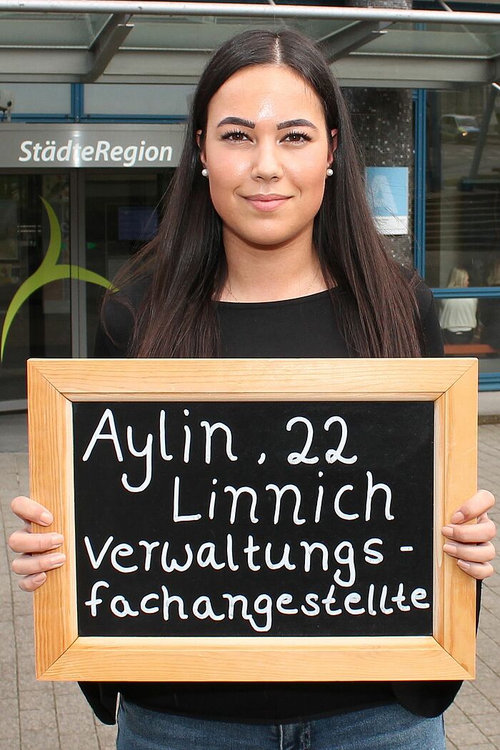 Aylin-Ayla Avci hält Tafel mit ihrem Namen, ihrem Alter und ihrem Ausbildungsberuf
