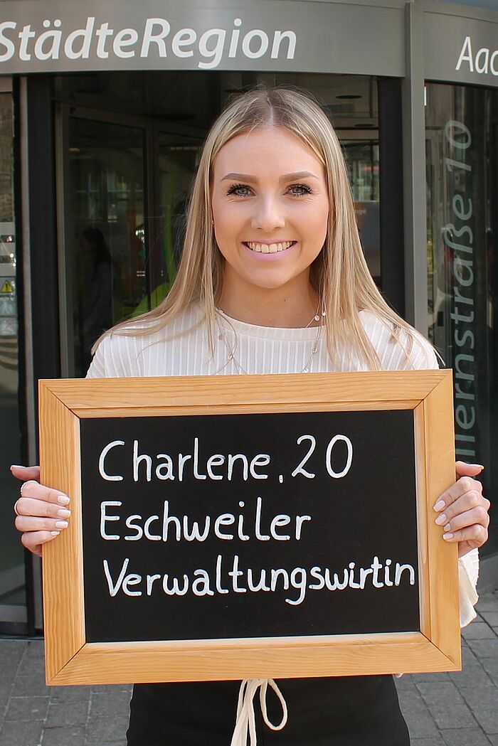 Charlene Schmidt hält Tafel mit ihrem Namen, ihrem Alter und ihrem Ausbildungsberuf