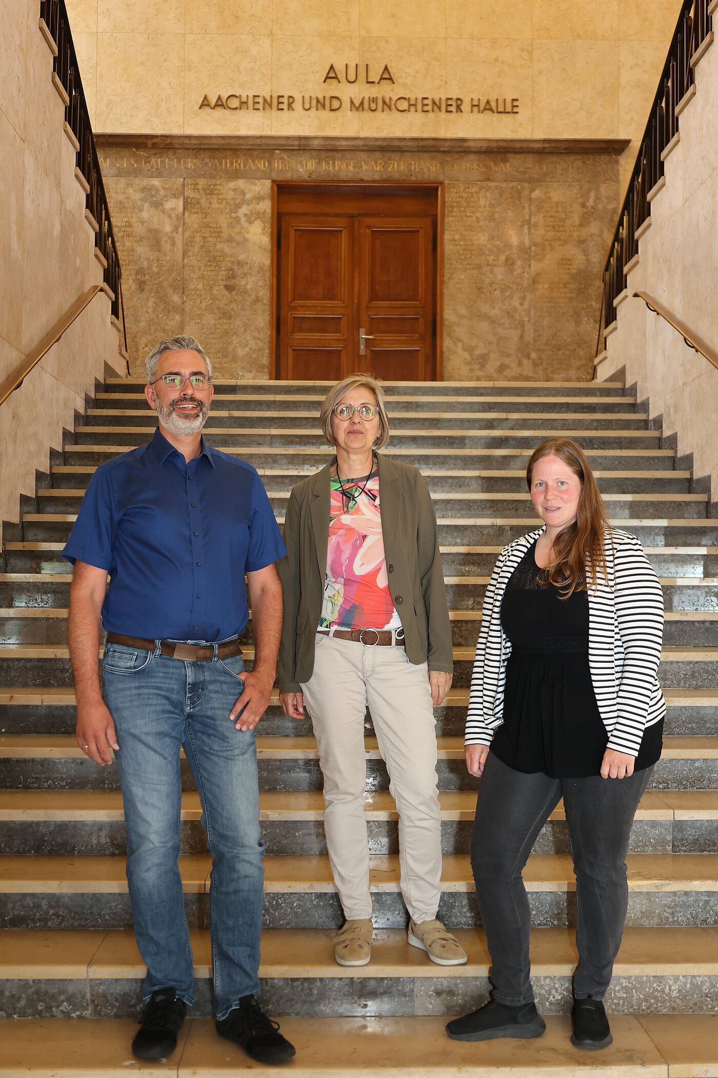 Zwei Frauen und ein Mann auf einer Treppe