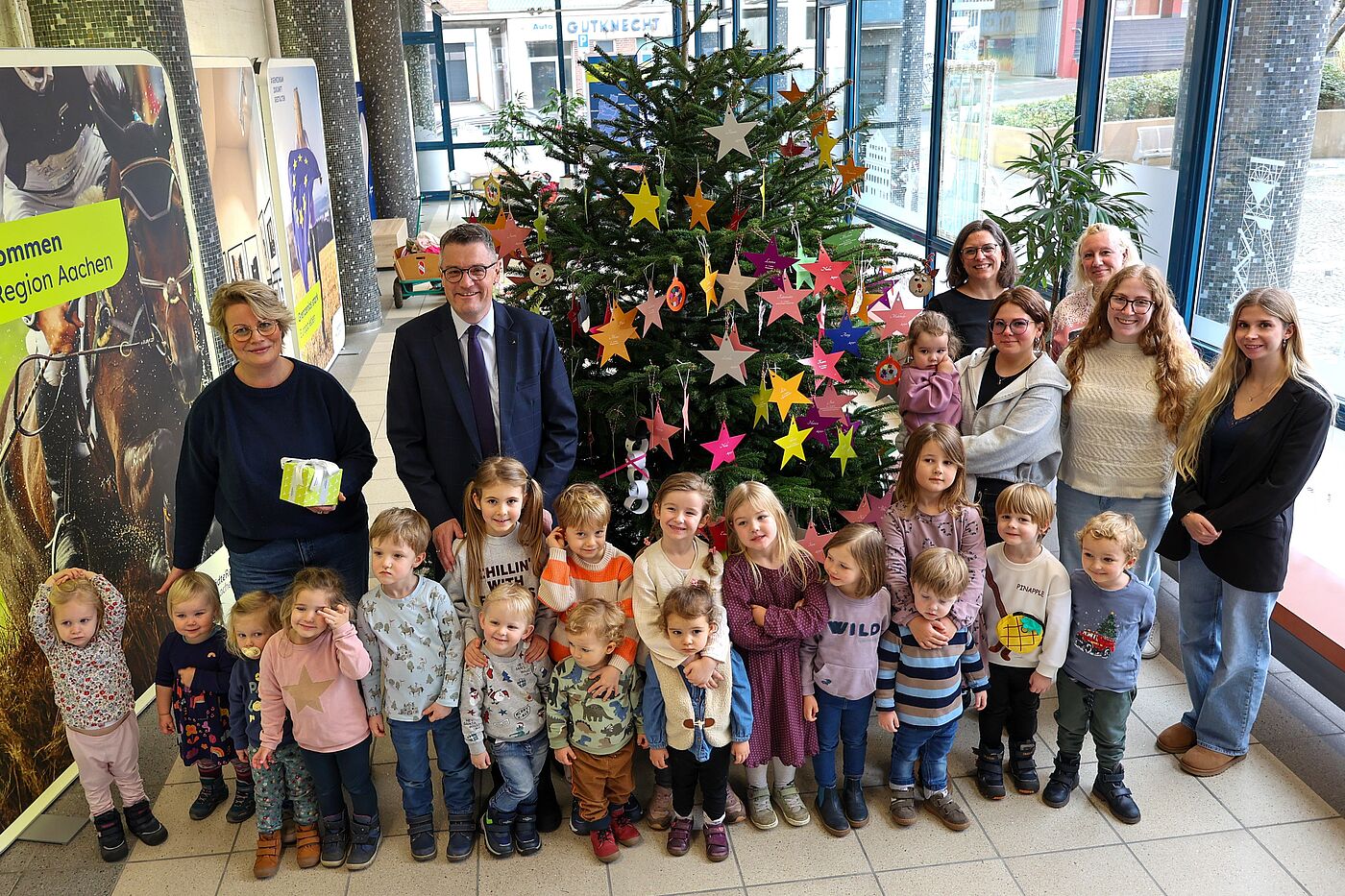 Mehrere Kinder und Erwachsene vor einem Weihnachtsbaum.