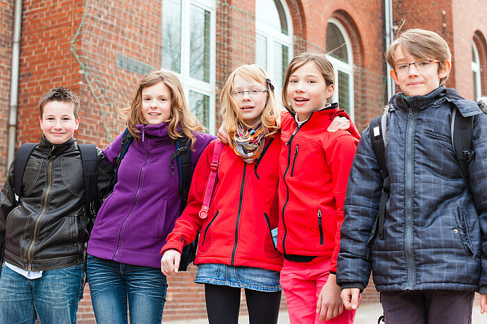 5 Schulkinder schauen in die Kamera