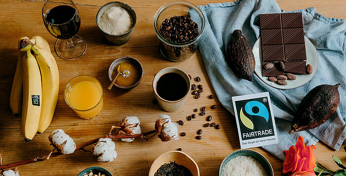 auf einem Tisch liegen Fairtrade-Produkte: Bananen, Kaffee, Schokolade, Reis, Honig