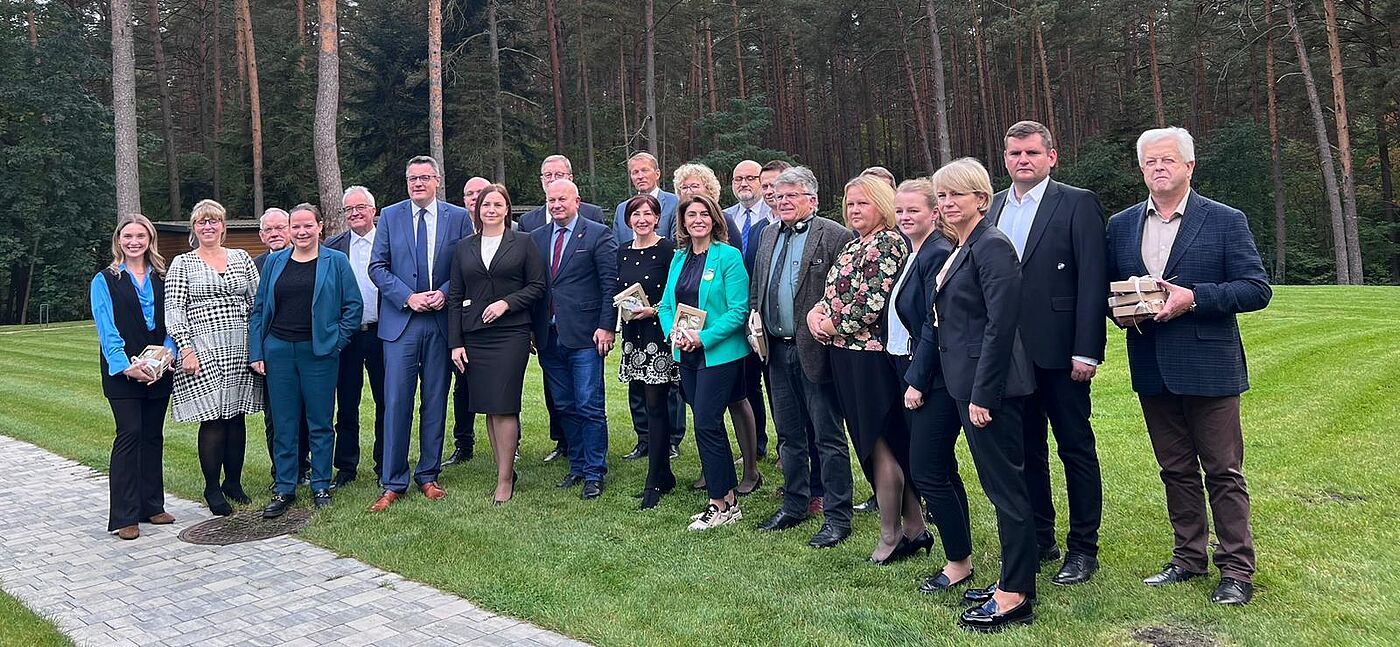 Mitglieder der Verwaltungen der StädteRegion Aachen, des Kreises Lubaczów und des Rajon Lwiw stehen gemeinsam auf einer Wiese.