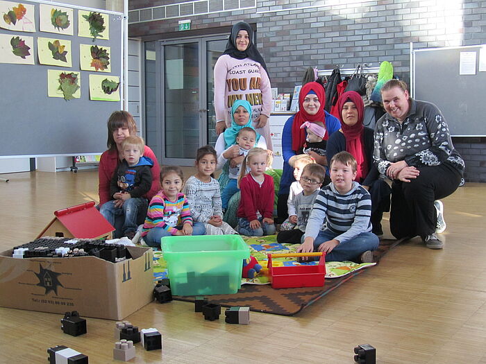 Gruppenfoto mit Müttrern und ihren Kindern inmitten von Spielzeug im Haus Setterich