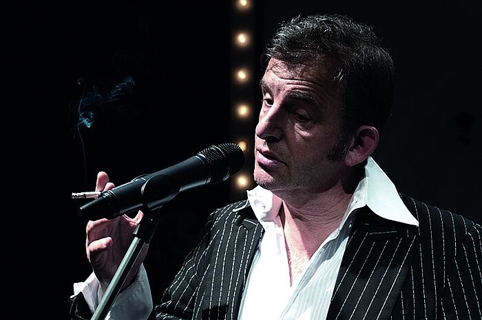 Der Schauspieler Dominique Horwitz auf der Bühne in Nahaufname, rauchend als Serge Gainsbourg