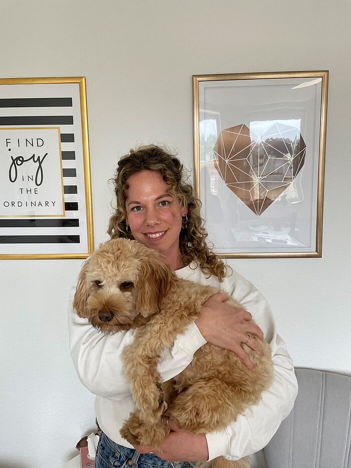 Eine Frau hält eine Australien Labradoodle-Hündin auf dem Arm.
