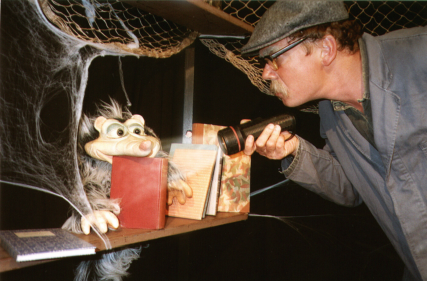 Ein Mann leuchtet in ein verstaubtes Regal mit einer Taschenlampe