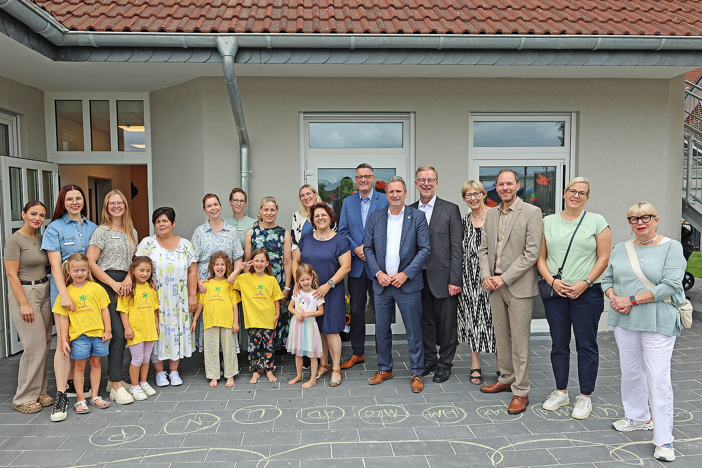 Mehrere Kinder und Erwachsene vor einer Kindertagesstätte.