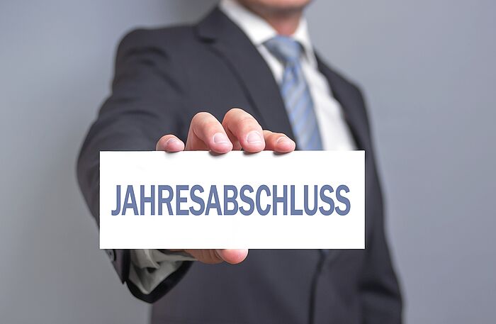 Mann hält ein Schild mit dem Wort Jahresabschluss