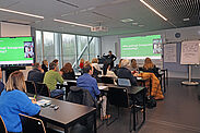 Etwa 20 Personen schauen sich in einem Workshop eine Präsentation an.