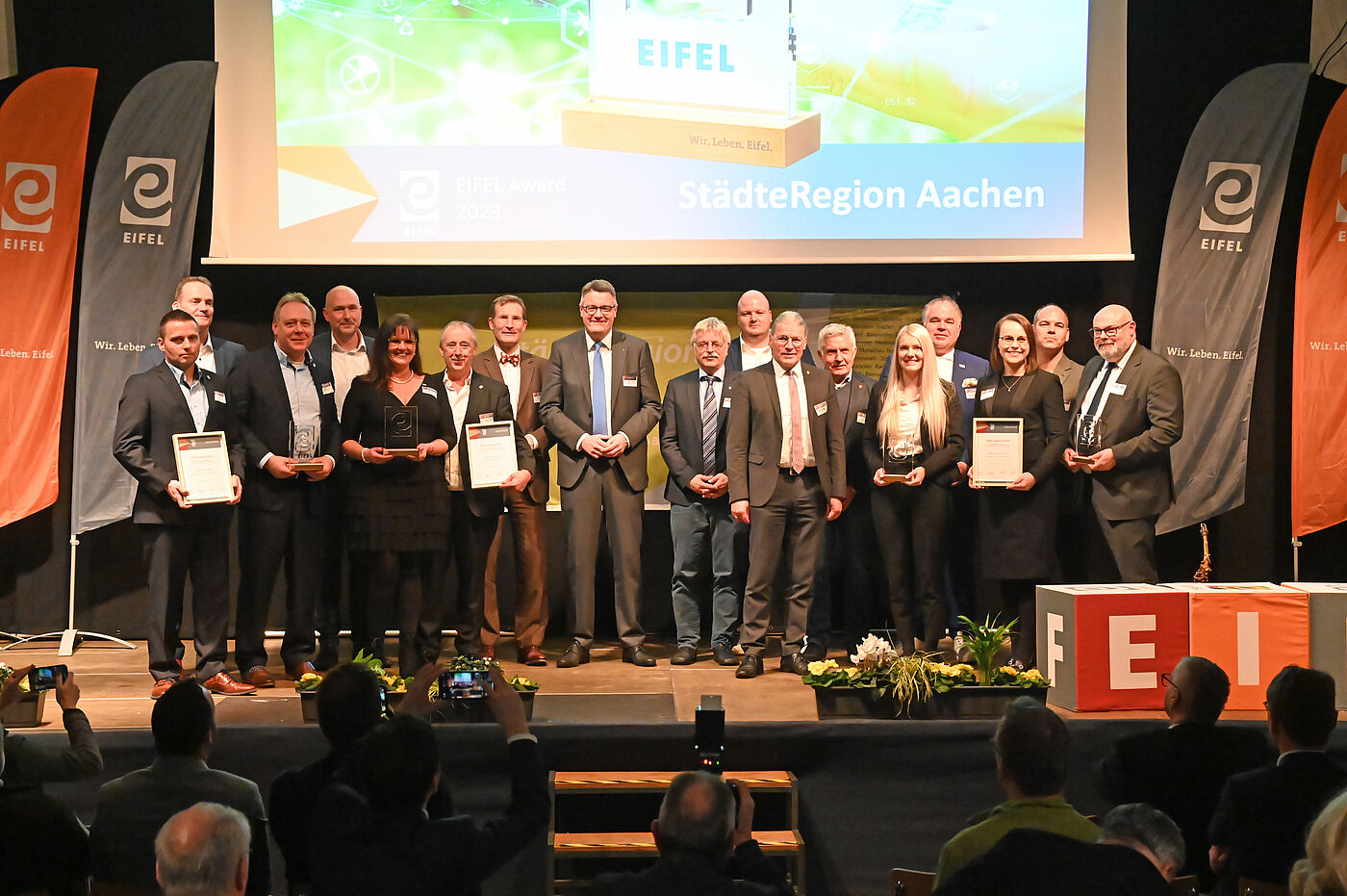 Der Städteregionsrat, kommunale Vertreter und die Preisträger stehen auf einer Bühne. Die Preisträger halten ihre Urkunden in der Hand.