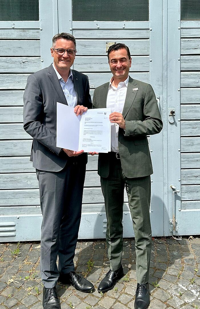 Städteregionsrat Dr. Tim Grüttemeier und Regierungspräsident Dr. Thomas Wilk stehen nebeneinander und halten den Haushaltsplan 2025 in der Hand.