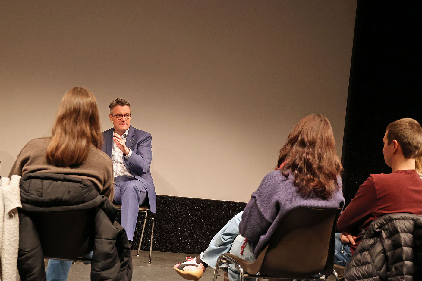 Ein Mann im Gespräch mit jungen Menschen, die vor ihm sitzen.