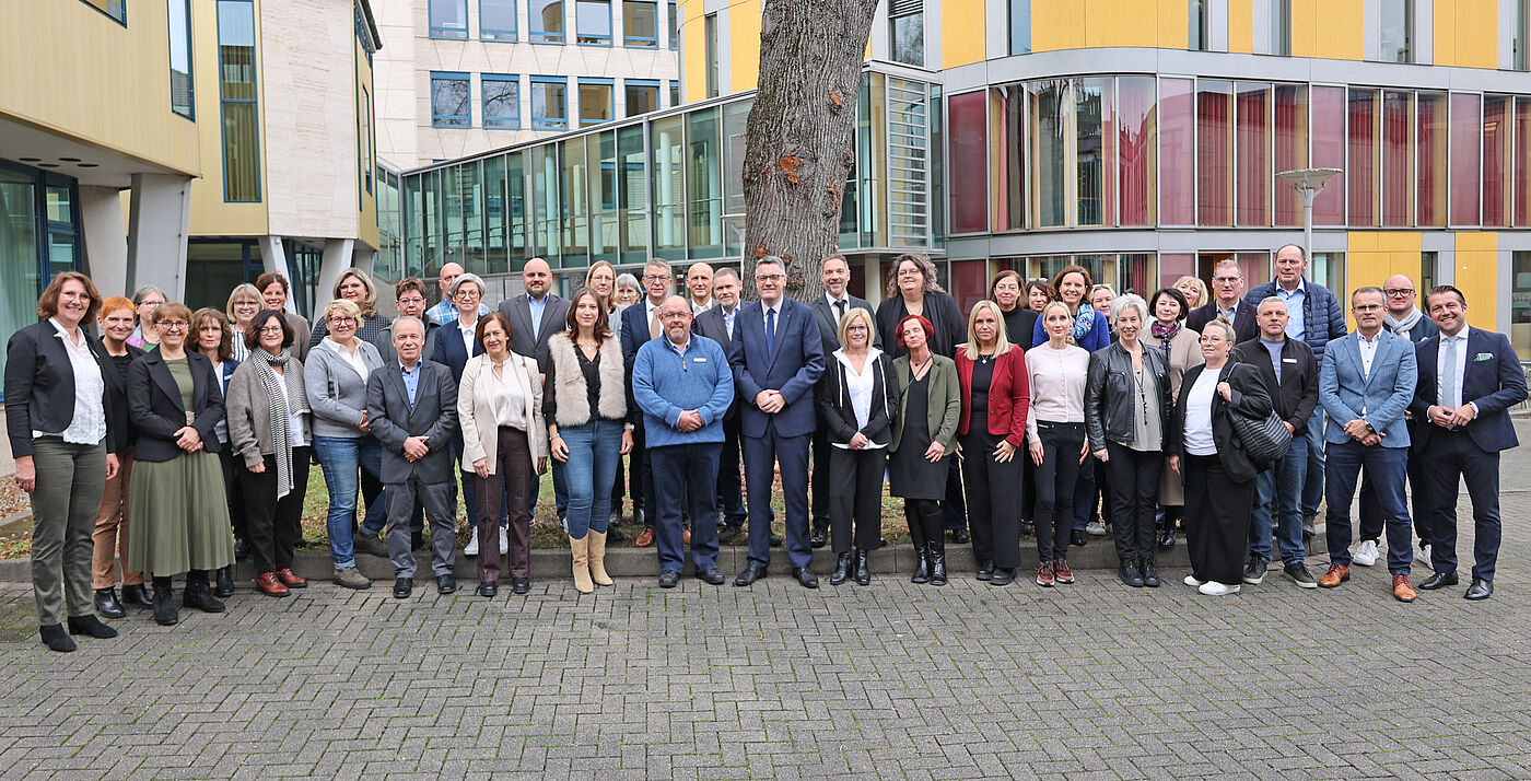 Viele Menschen auf einem Gruppenbild vor einem gelben Gebäude.