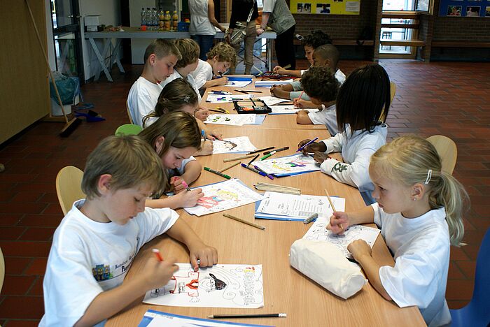 Kinder sitzen an einem Tisch und malen 
