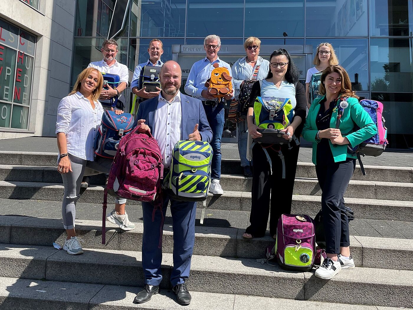 Dr. Michael Ziemons (Mitte) bedankt sich bei allen, die zum Erfolg der Aktion „Schulranzen für die Ukraine“ beigetragen haben: (v.l.n.r.) Pelin Yigit (Türöffner e.V.), Maciej Lukomski (Werbeagentur Afterglow und Öcher Fans för Kenger e.V.), Klaas Wolters (Weyers-Katzers), Markus Frankenne (Frankenne), Ulrike Thönniges (Tatort e.V.), Dr Kateryna Kravchenko (Blau-Gelbes Kreuz e.V.), Cordula Eiche (Tatort e.V.) und Linda Mai (Blau-Gelbes Kreuz e.V.).