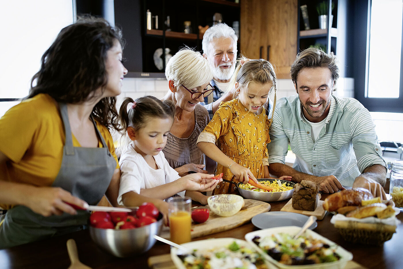 Eine Familie sitzt genrationsübergreifend an einem Tisch und kocht gemeinsam