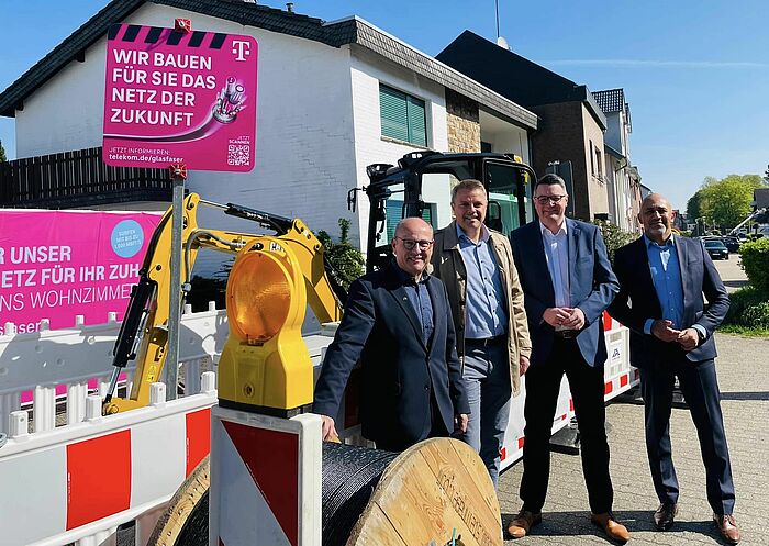 Vier Personen stehen vor einer Baustelle der Telekom