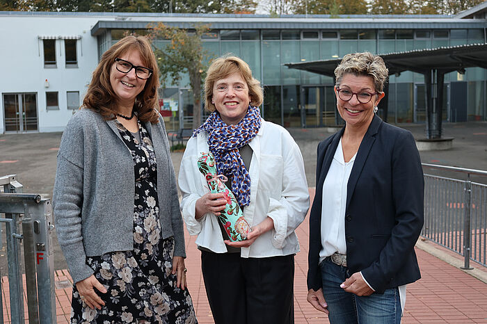 Drei Frauen auf einem Schulhof.