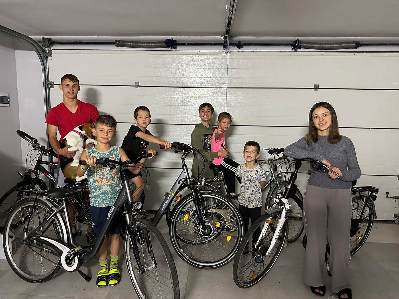 Jugendliche mit Fahrrädern in einer Garage.