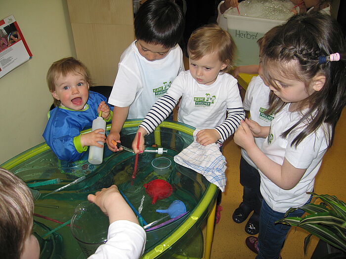 Kindergartenkinder machen Experimente an einem Planschbecken