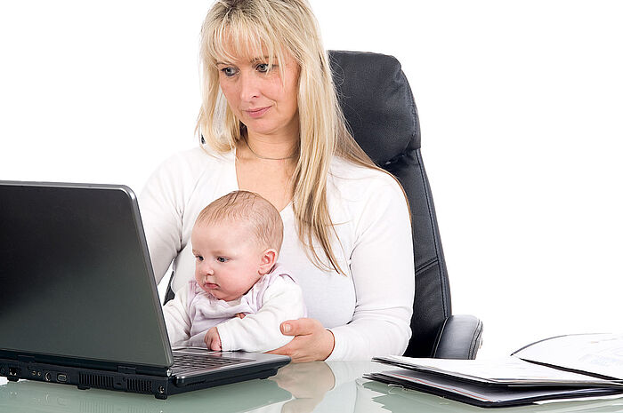 Mutter mit Baby vor einem Laptop
