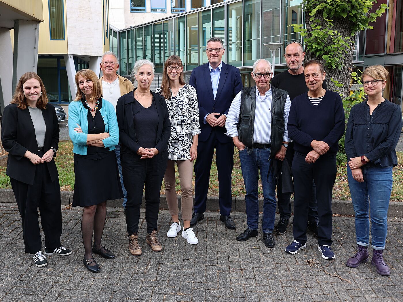 Mehrere Menschen nebeneinander vor einem Baum.