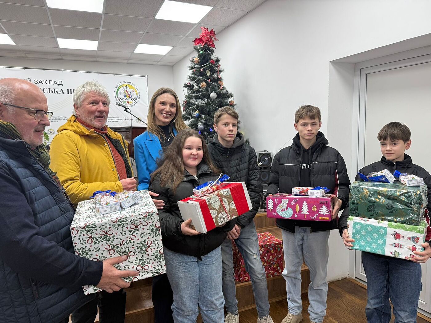 Kinder und Erwachsene mit Weihnachtsgeschenken in der Hand.