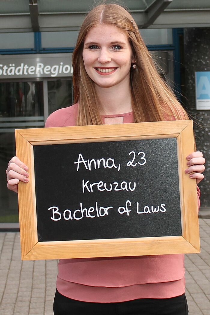 Anna Schmitz hält Tafel mit ihrem Namen, ihrem Alter und ihrem Ausbildungsberuf