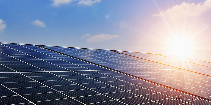 blauer Himmel, Sonne und ein Dach mit Solarpaneelen