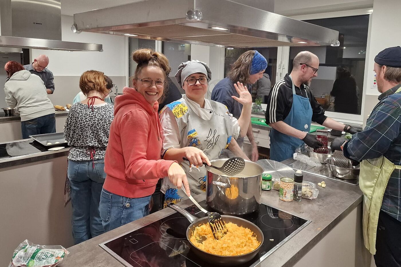 Mehrere Menschen kochen zusammen in einer Großküche.