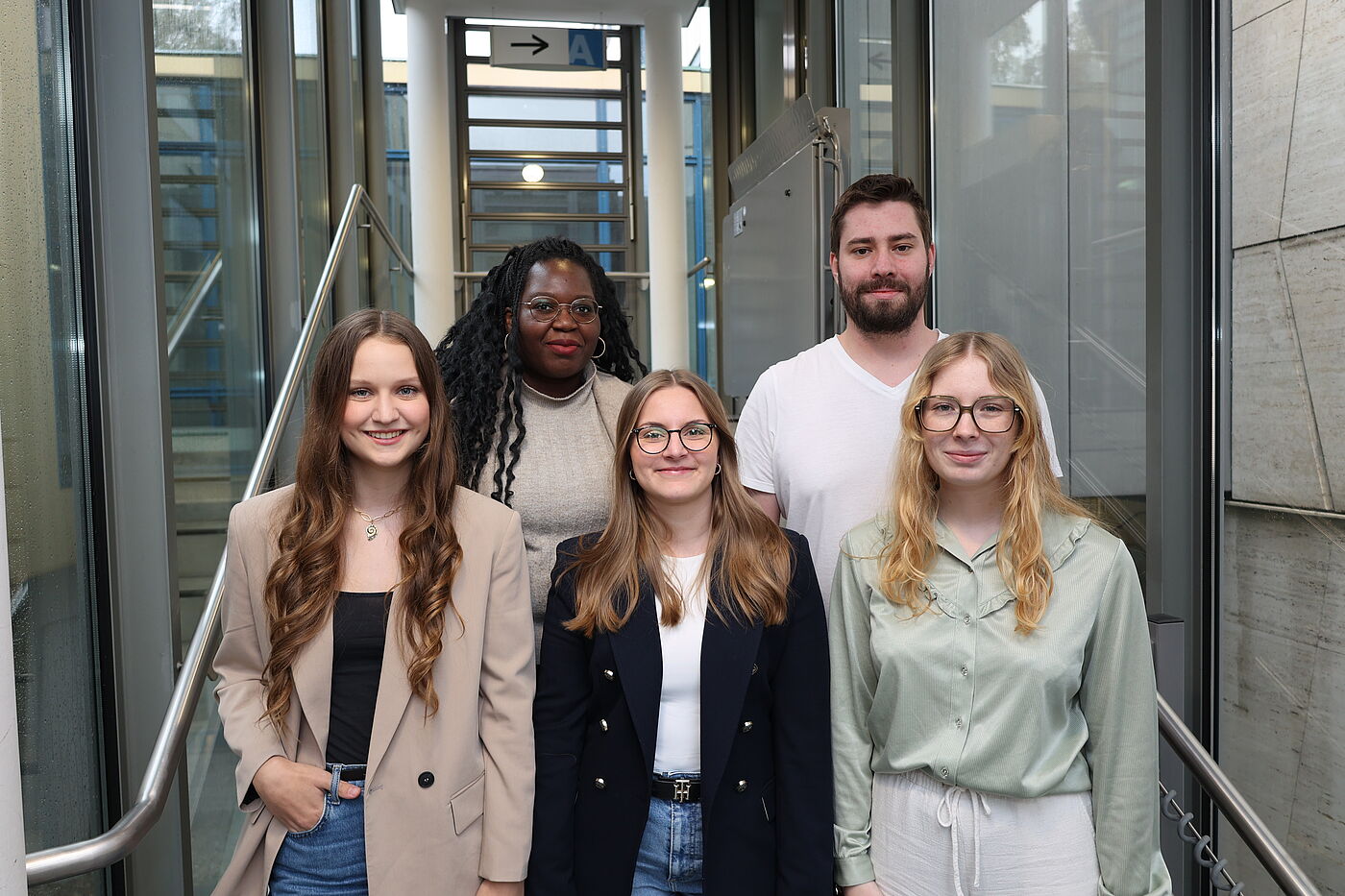 Vier junge Frauen und ein junger Mann auf einer Treppe.