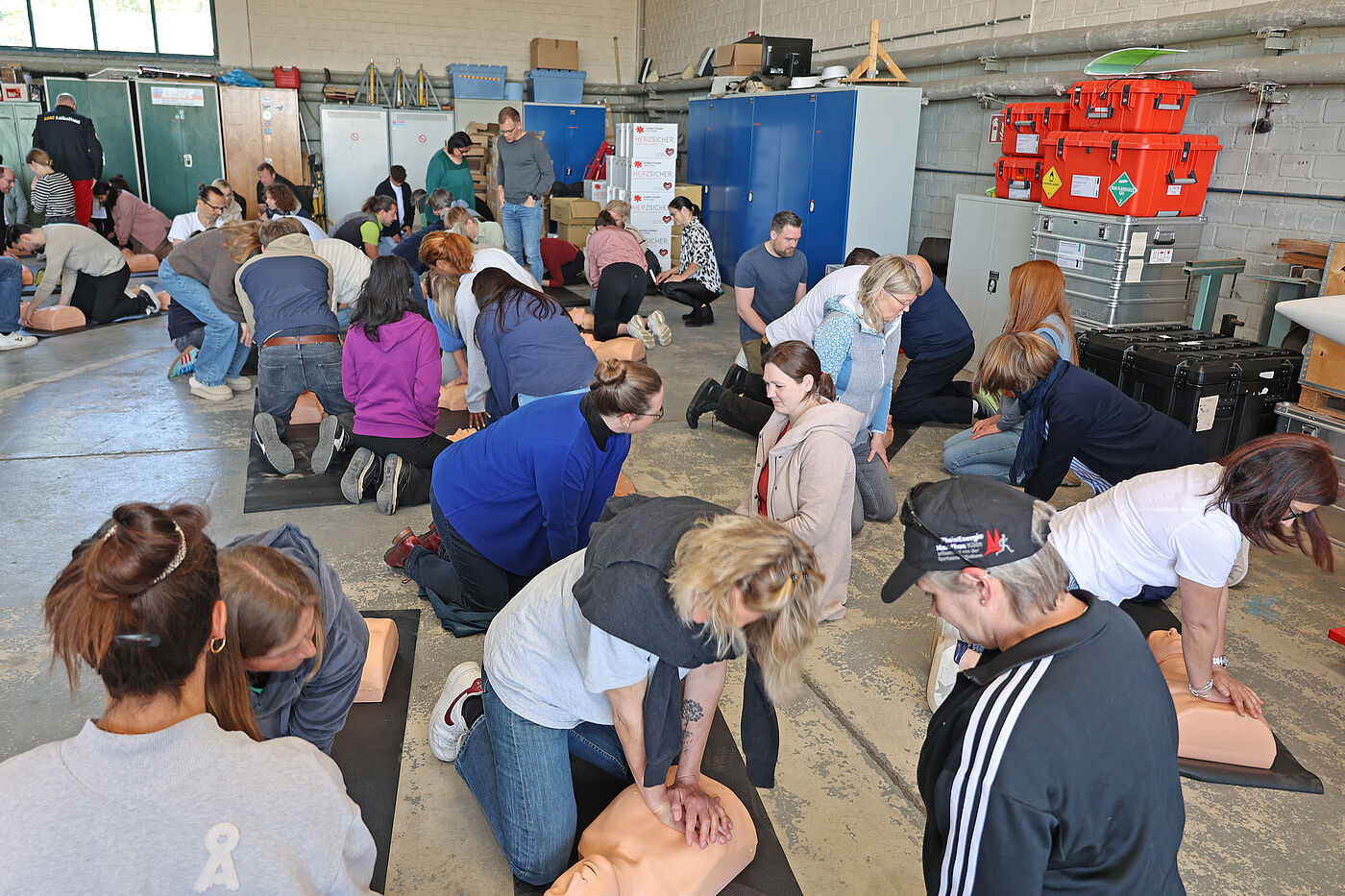 Mehrere Menschen drücken auf Puppen herum und simulieren Lebensrettung.