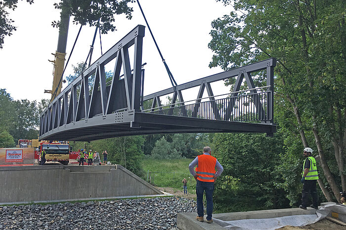 Eine Brücke wird mit einem Kran über einen Fluss gelegt