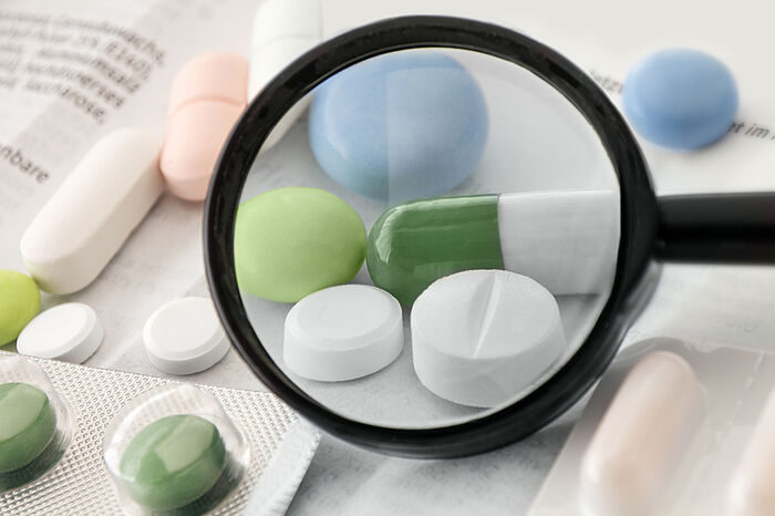 Verschiedene Tabletten mit einer Lupe im Vordergrund