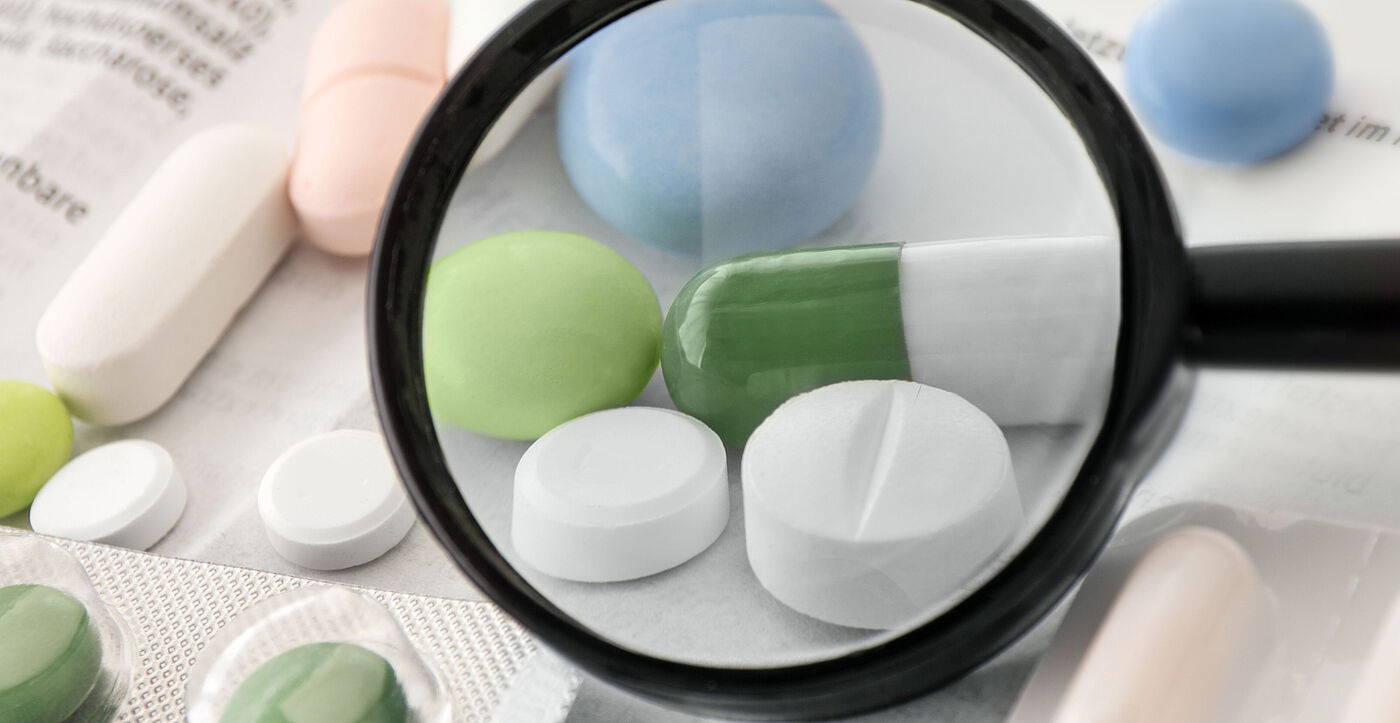 Verschiedene Tabletten mit einer Lupe im Vordergrund