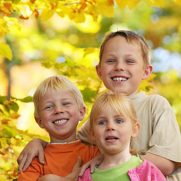 Drei fröhliche Kinder lächeln in die Kamera