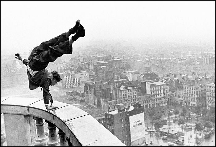 Mann auf einer sehr hohen Ballustrade Handstand machend.