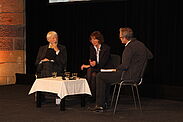 Jan und Aleida Assmann im Gespräch mit Moderator Martin Schult auf der Bühne im Krönungssaal. 
